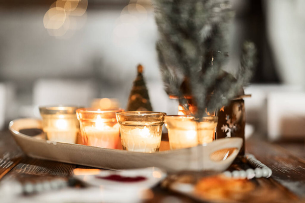 set of burning candles, small artificial Christmas trees and plates with spices on a wooden brown table, Christmas and New Year's concept, selective focus - Foto, Imagem