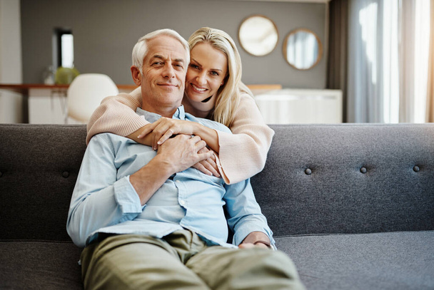 Love each other...a lot. a mature woman hugging her husband on the sofa at home - 写真・画像