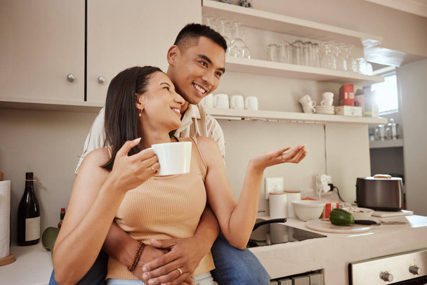 Счастливая, любящая и романтичная пара обнимается, стоя дома на кухне. Муж и жена разговаривают, любят и наслаждаются ощущением беззаботности, выпивая чашку кофе по утрам. - Фото, изображение