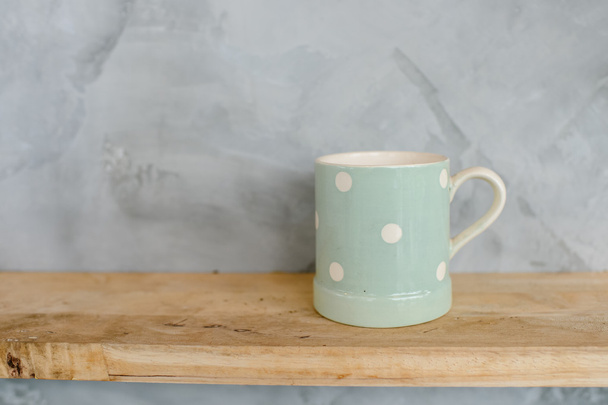 Pastel Green cup with dot on wooden background and cement wall. - Фото, изображение