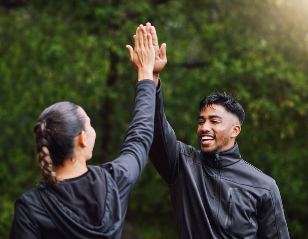 Active, fit and sporty athletes doing a high five to celebrate and congratulate on fitness goals. Healthy, happy and exercising couple motivated after training, getting cardio workout outside. - Photo, image