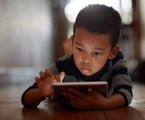 Исследую мир приложений. мальчик использует свой цифровой планшет, лежа на полу дома - Фото, изображение
