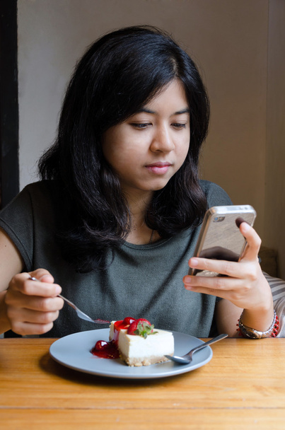 Mladá asijská žena chating mobilní telefon s dort - Fotografie, Obrázek
