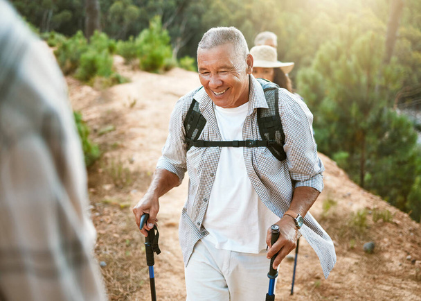 Hike, trekking sticks and senior male walking with friends for fitness and health in nature. Healthy, active and smiling mature man hiking with a backpack. Old group on an outdoor wellness adventure. - Zdjęcie, obraz