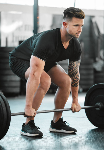 Fit, active and strong man with barbell weight for lifting in gym workout, exercise and training. Serious, motivated and sporty athlete building muscle, cardio health and endurance in wellness centre. - Foto, imagen