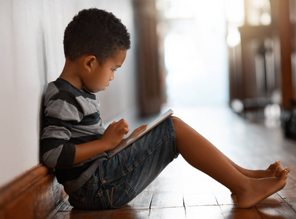 Технологии все включено. Снимок мальчика в полный рост, сидящего дома на полу с помощью цифрового планшета - Фото, изображение