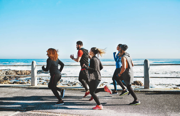 Friends offer encouragement to keep you going. a fitness group out running on the promenade - Photo, Image