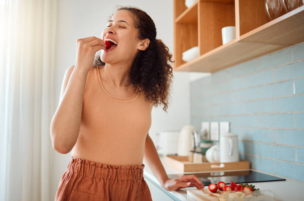 Eating, chopping or making fruit salad with strawberries, bananas or healthy ingredients in home kitchen. Smiling or happy woman cooking, biting and tasting fresh snack food or preparing breakfast. - Photo, image