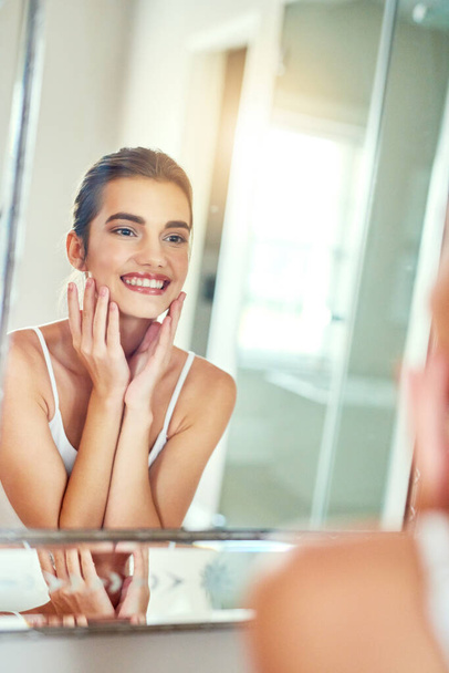 О, такая сказочная кожа просто лучшая. привлекательная молодая женщина осматривает свою кожу в зеркале - Фото, изображение