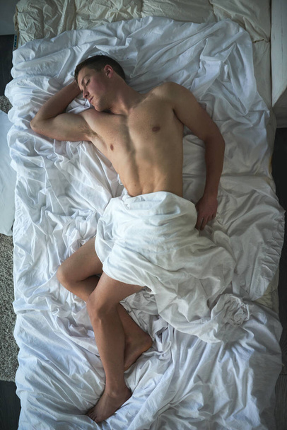 Its too hot for sheets. a shirtless young man sleeping in his bedroom - Zdjęcie, obraz