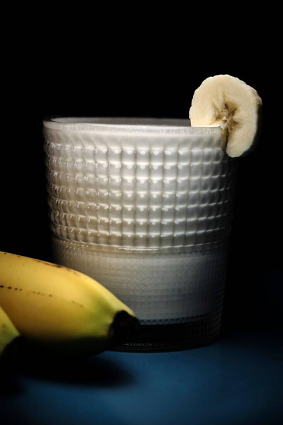 A low key darker shot of the banana milk shake with actual banana - Photo, Image