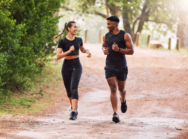 Fitness, exercise and happy couple out running or jogging on a forest trail or park outdoors. Sporty and smiling man and woman staying active and fit while exercising and bonding during a workout. - Photo, image