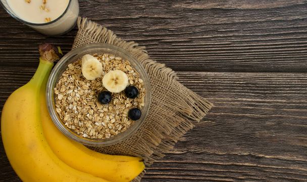 Banana, oatmeal, milk on a wooden background - Fotoğraf, Görsel