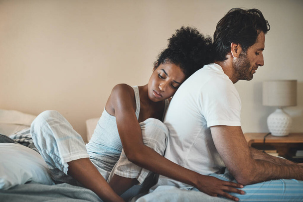 Woman tries to embrace her husband with affection after their fight at home. Unhappy interracial couple with marriage problems forgive each other. Empathy and guilty feelings after the affair - 写真・画像