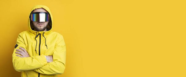 Νεαρός με γυαλιά εικονικής πραγματικότητας με κίτρινο μπουφάν σε κίτρινο φόντο. Μπάνερ. - Φωτογραφία, εικόνα