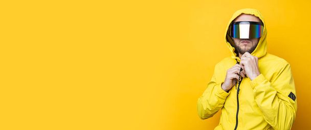 Young man in cyberpunk glasses in a yellow jacket on a yellow background. Banner. - Foto, Bild