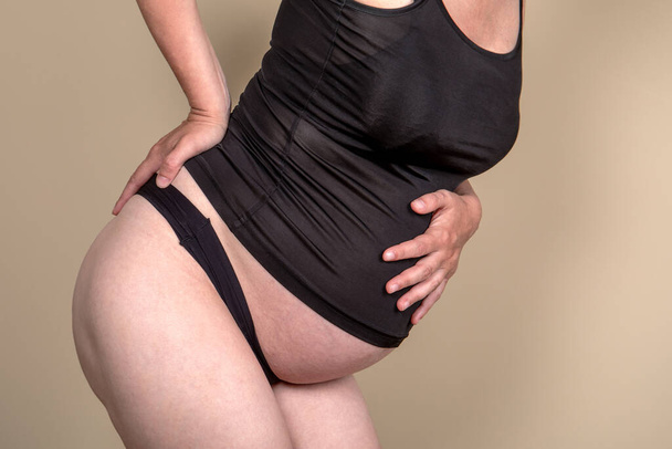 The pregnant woman holds her stomach and back. Back pain during pregnancy.. - Photo, image
