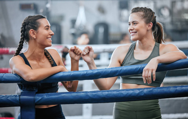 Giving support, motivation and bumping fists after being active, exercising and training in ring. Team of female boxers, fighters or sports athletes standing together in a gym, fitness center or club. - 写真・画像