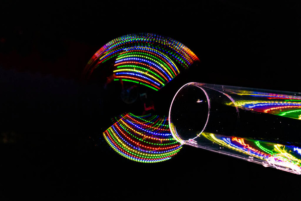 эффектные цветные огни, отраженные в мыльном пузыре, созданном через прозрачную трубку - Фото, изображение