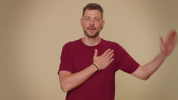 I swear to be honest. Sincere responsible handsome young man raising hand to take oath, promising to be honest and to tell truth, keeping hand on chest. Adult stylish guy isolated on beige background - Záběry, video
