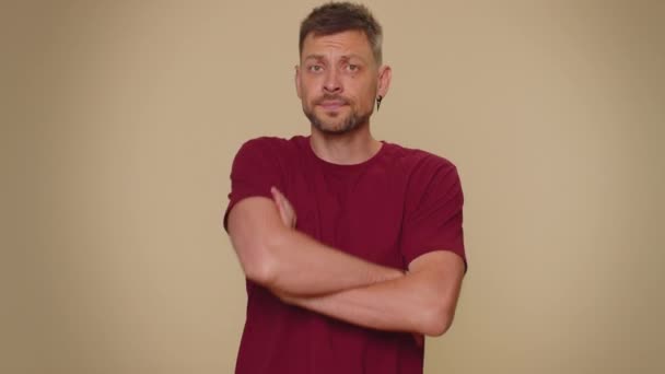 Offended handsome young man having misunderstanding, frustrated after quarrel, ignores and does not want to communicate, talk. Adult stylish male guy isolated on beige studio background indoors - Felvétel, videó