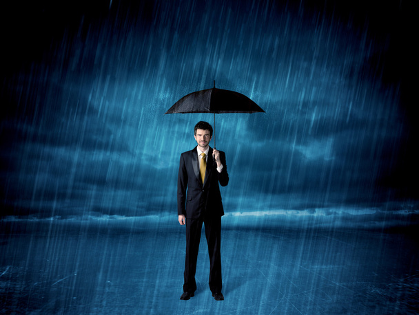 Business man standing in rain with an umbrella - Valokuva, kuva