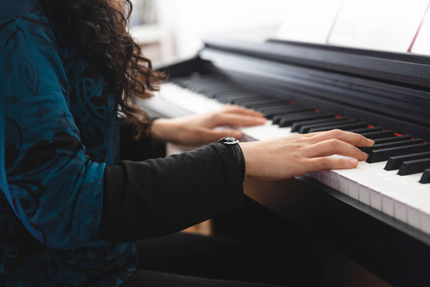 Close up of womans hands playing piano by reading sheet music. High quality photo - Photo, Image