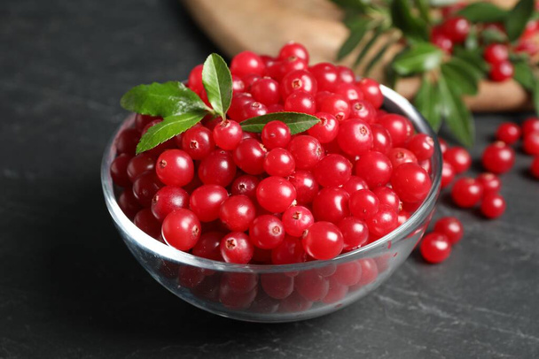 Fresh cranberry in bowl on dark grey table, closeup - 写真・画像
