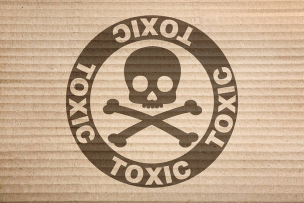 Hazard warning sign (skull-and-crossbones symbol and word TOXIC) on cardboard, top view - Photo, image