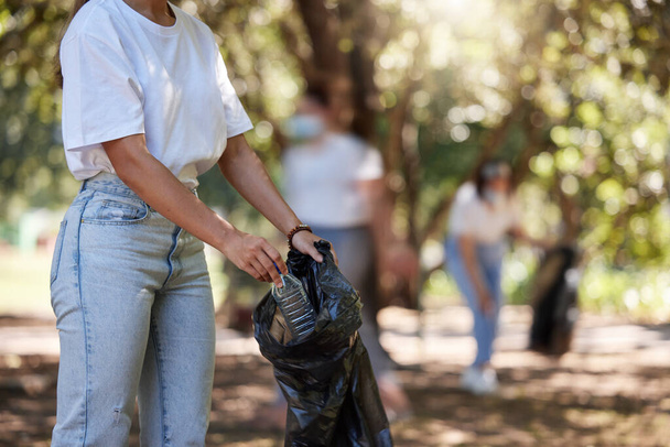 Volunteer, recycle and reduce global waste by picking up litter, dirt and garbage outdoors in a park. Closeup of young female NGO activist cleaning pollution from the environment for sustainability. - Foto, Imagem