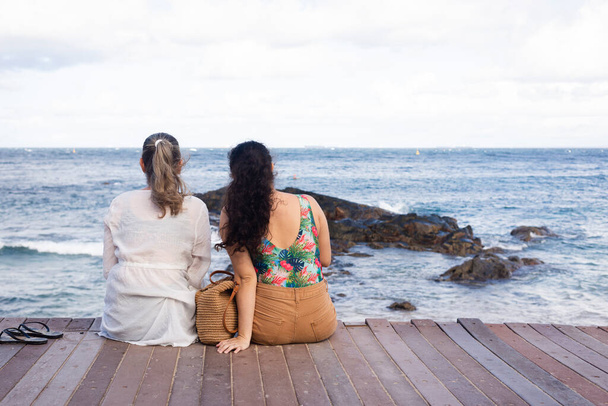 Mother and daughter sitting on the pier of the port of Barra facing the sea. Salvador, Bahia, Brazil. - Foto, Imagem