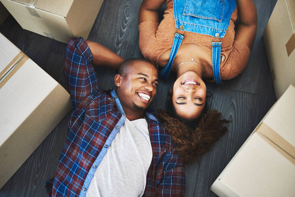С тобой. Я дома. Высокоугольный снимок привлекательной молодой пары, лежащей на полу в своем новом доме - Фото, изображение