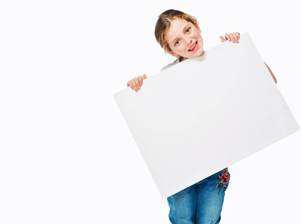 Use this space to spread the word. Studio shot of an adorable little girl holding a blank placard - Fotografie, Obrázek