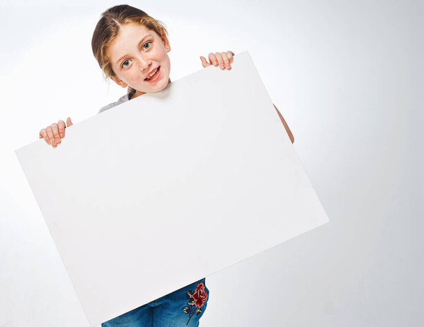 Ill share your message. Studio shot of an adorable little girl holding a blank placard - 写真・画像