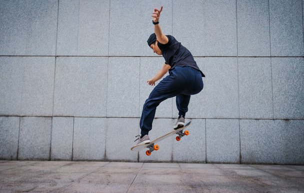 Asian woman skateboarder skateboarding in modern city - Foto, Imagem