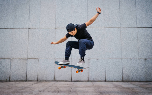 Asian woman skateboarder skateboarding in modern city - Valokuva, kuva