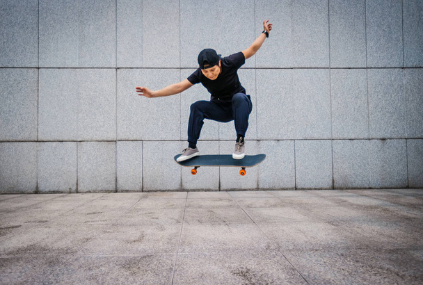 Asian woman skateboarder skateboarding in modern city - Фото, изображение