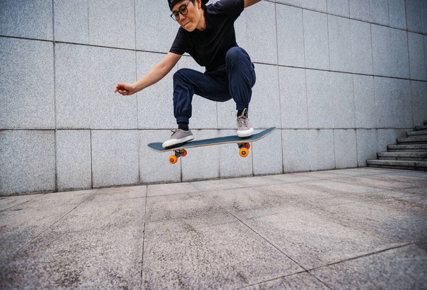 Asian woman skateboarder skateboarding in modern city - Фото, зображення