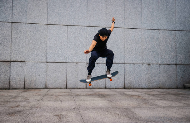 Asian woman skateboarder skateboarding in modern city - Foto, immagini