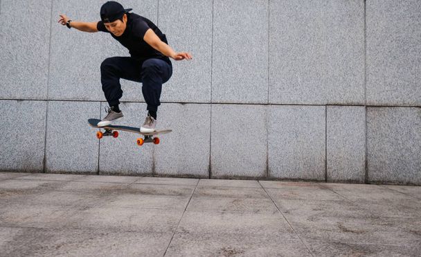 Asian woman skateboarder skateboarding in modern city - Zdjęcie, obraz