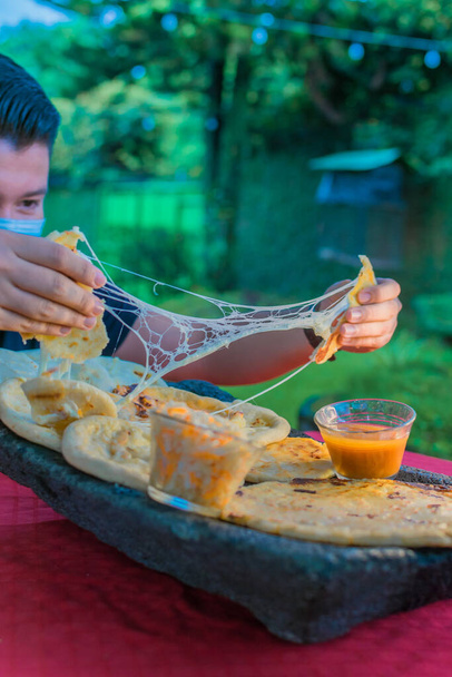 Типова сальвадорська страва, сирні ляльки з капустою і томатним соусом. рис і кукурудзяні ляльки, наповнені сиром, квасолею та іншими інгредієнтами. - Фото, зображення