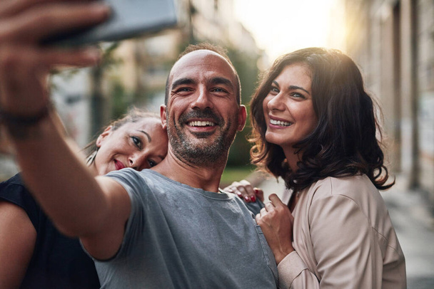 Selfie with my closest friends. three friends taking a selfie while enjoying themselves out in the city - Foto, Imagen