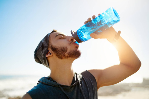 Your body cant perform at its best if youre not hydrated. a sporty young man drinking water while exercising outdoors - Fotó, kép