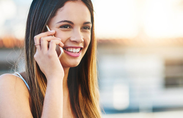 Connected across the globe. an attractive young woman making a phone call while standing outside - Foto, Imagen