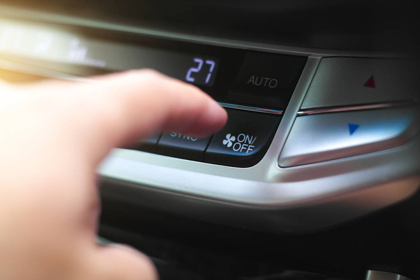 Рука водителя нажимает кнопку включения автокондиционера в автомобиле. - Фото, изображение