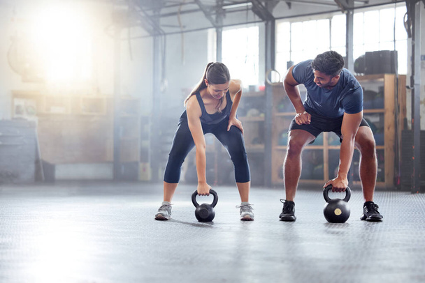 Fitness couple doing a kettlebell workout, exercise or warmup training in a gym. Fit sports people, woman and man with a strong grip, exercising using equipment to build muscles and forearm strength - Valokuva, kuva
