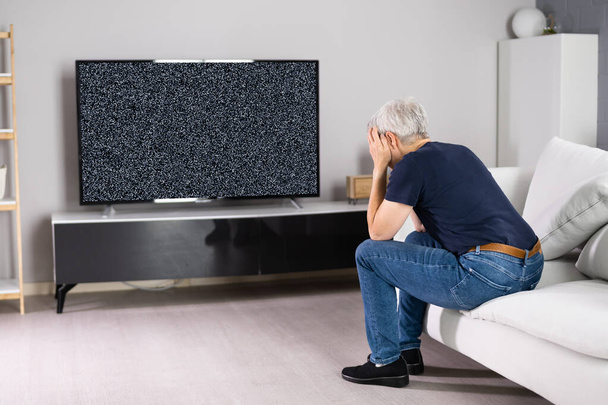 Sad Woman With Remote Sitting On Sofa Near Television With No Signal - Photo, Image
