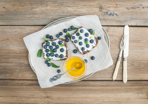 リコッタ チーズ、新鮮なブルーベリー、蜂蜜入り健康的な朝食と - 写真・画像