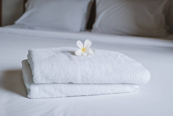 Плюмерія і рушники на ліжку в розкішному готельному номері готові для туристичних подорожей.. - Фото, зображення
