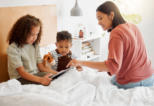 Mother and children browsing a digital tablet in the bed at home, bonding and learning to use technology. Family on the internet online to play games and learn from educational apps or website. - Zdjęcie, obraz